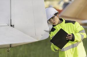 tecnico che ripara il motore dell'aereo, ingegneria aerospaziale femminile che controlla i motori degli aerei, manutenzione meccanica asiatica ispeziona il motore dell'aereo foto