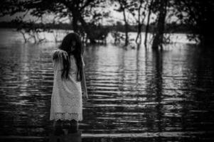 ritratto di asiatico donna rendere su fantasma viso a il palude, orrore nel acqua scena, spaventoso a fiume, halloween manifesto, thailandia persone foto