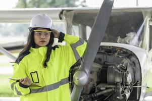 tecnico che ripara il motore dell'aereo, ingegneria aerospaziale femminile che controlla i motori degli aerei, manutenzione meccanica asiatica ispeziona il motore dell'aereo foto