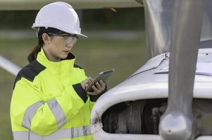 tecnico che ripara il motore dell'aereo, ingegneria aerospaziale femminile che controlla i motori degli aerei, manutenzione meccanica asiatica ispeziona il motore dell'aereo foto