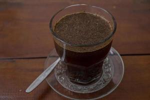 vicino su foto un' tazza di arabica caffè con cucchiaio a partire dal alto angolo. il foto è adatto per uso per caffè negozio sfondo, menù manifesto e caffè soddisfare media.