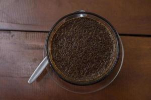 vicino su foto un' tazza di arabica caffè con cucchiaio a partire dal alto angolo. il foto è adatto per uso per caffè negozio sfondo, menù manifesto e caffè soddisfare media.