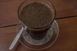 vicino su foto un' tazza di arabica caffè con cucchiaio a partire dal alto angolo. il foto è adatto per uso per caffè negozio sfondo, menù manifesto e caffè soddisfare media.