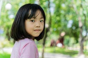ritratto di bella bambino ragazza in piedi nel estate parco. contento sorridente bambini all'aperto foto