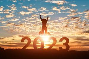 silhouette di donna salto per contento nuovo anno 2023 nel tramonto o Alba sfondo. foto