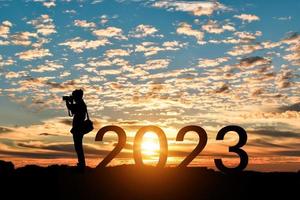 silhouette di fotografo assunzione fotografie nel 2023 anni a Alba o tramonto sfondo. idea per contento nuovo anno 2022.