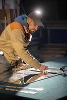 un' Lavorando uomo tagli un' specchio con un' bicchiere taglierina. foto