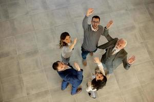 aereo Visualizza a contento attività commerciale persone aumentare mani insieme con gioia e successo nel il ufficio corridoio foto