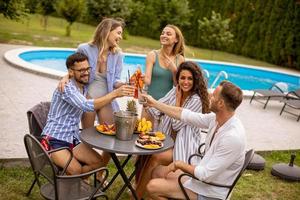 gruppo di giovane persone applauso con Cedro di il piscina nel il giardino foto