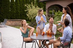 gruppo di giovane persone applauso con Cedro e mangiare Pizza di il piscina nel il giardino foto