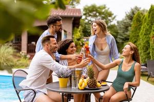 gruppo di giovane persone applauso con Cedro di il piscina nel il giardino foto