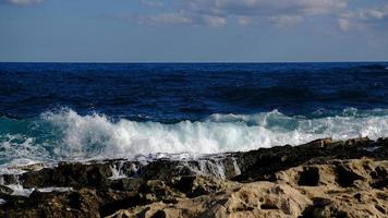 blu mare onda e bianca schiuma e spruzzata. pietra spiaggia su isola di Malta, no sabbioso spiaggia. estate vacanza confine telaio concetto. tropicale isola vacanza sfondo. turista viaggio bandiera design modello. foto