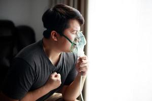 malato asiatico giovane uomo utilizzando nebulizzatore per asma e respiratorio malattie a casa. foto