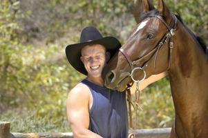 un' bello cowboy prende un' bacio a partire dal il suo cavallo nel un' divertimento servizio fotografico. foto