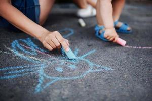 Close up di bambini che disegnano con il gesso sul marciapiede foto