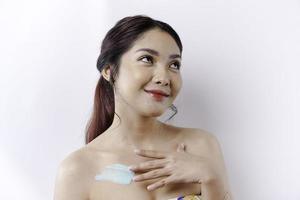 pelle cura prodotti concetto. asiatico donna l'applicazione idratante lozione su corpo dopo doccia, in piedi avvolto nel asciugamano, ritagliata Immagine foto