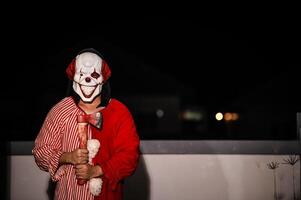 asiatico bello uomo indossare clown maschera con arma a il notte scena, halloween Festival concetto, orrore pauroso foto di un' uccisore nel arancia stoffa, male clown charactor