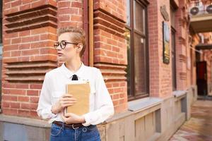 bella donna con bicchieri a piedi in giro il città con un' libro formazione scolastica foto