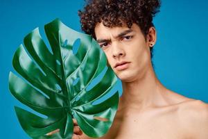 uomo con Riccio capelli nudo le spalle verde le foglie ecologia foto