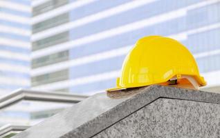 giallo sicurezza casco su costruzione luogo con edificio sfondo foto