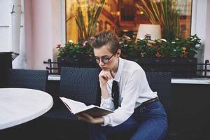 corto dai capelli donna con un' libro nel il suo mani lettura formazione scolastica foto