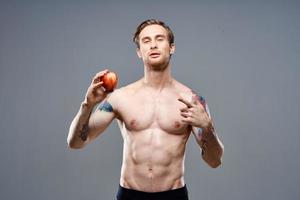 atletico tipo con un' pompato su torso salutare stile di vita nutrizione vitamine rosso Mela foto