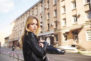 un' donna nel un' nero giacca passeggiate giù il strada nel il città ritagliata Visualizza foto