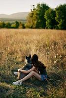 donna seduta nel campo con bassotto cane sorridente mentre la spesa tempo nel natura con amico cane nel autunno a tramonto mentre in viaggio foto