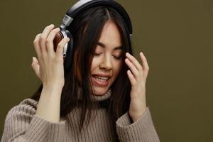 giovane donna nel un' maglione ascoltando per musica con cuffie divertimento studio modello foto