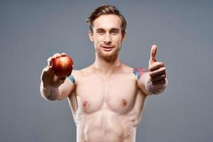 atletico tipo con un' pompato su torso salutare stile di vita nutrizione vitamine rosso Mela foto
