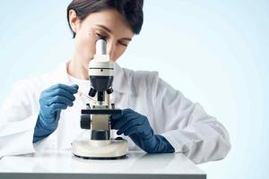 donna nel bianca cappotto microscopio ricerca diagnostica professionisti foto