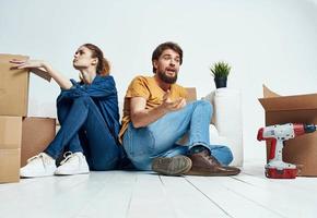 uomo e donna seduta su il pavimento con loro schiene per ogni altro rinnovamento opera in movimento un' fiore nel un' pentola foto