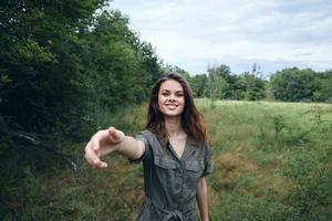 donna ritratto su natura nel un' verde tuta da lavoro Sorridi con un disteso mano foto