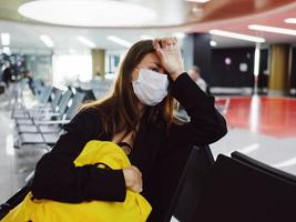 donna Tenere mano su testa medico maschera in attesa passeggeri aeroporto foto
