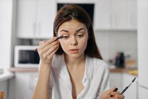 donna modello con eyeliner matita nel mano nel il cucina foto