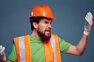 barbuto uomo nel arancia difficile cappello guanti professionale ritagliata Visualizza blu sfondo foto