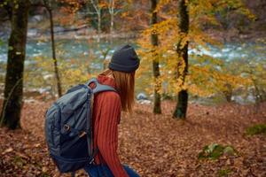 donna con zaino viaggio turismo foresta paesaggio parco fiume caduto le foglie lato Visualizza foto