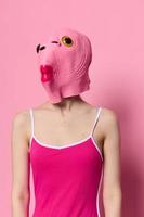 donna nel un' pesce costume per Halloween pose contro un' rosa sfondo nel un' pazzo pauroso costume con un' rosa silicone maschera su sua testa foto