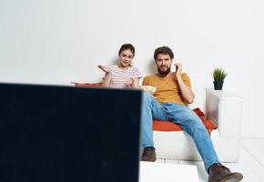 uomo e donna su il divano Guardando tv fiore in vaso foto