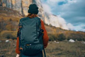 donna escursionista con un' zaino viaggi nel il montagne all'aperto nel autunno caduto le foglie foto