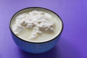 yogurt fresco in una ciotola su sfondo viola foto