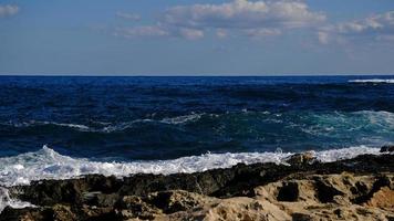 blu mare onda e bianca schiuma e spruzzata. pietra spiaggia su isola di Malta, no sabbioso spiaggia. estate vacanza confine telaio concetto. tropicale isola vacanza sfondo. turista viaggio bandiera design modello. foto