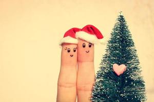 dito arte di coppia celebra Natale. concetto di uomo e donna ridendo nel nuovo anno cappelli vicino Natale albero. tonica Immagine foto