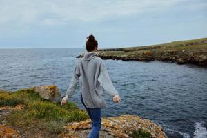 bellissimo donna nel un' grigio maglione sta su un' roccioso riva natura rilassamento concetto foto