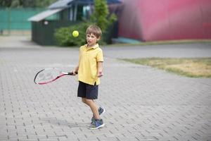 bambino con un' tennis racchetta e un' sfera. ragazzo tennis giocatore. scolaro va nel per gli sport foto