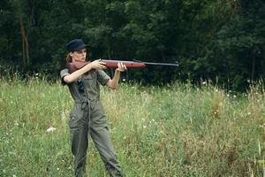 donna su natura verde tuta da lavoro con un' pistola nel davanti di lui fresco aria foto