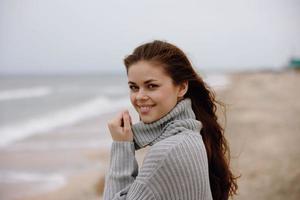 ritratto di un' donna nel un' maglione volante capelli di il oceano turismo contento femmina rilassante foto