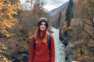 bella donna escursionista nel autunno Abiti nel il montagne vicino il fiume natura foto