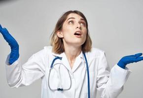 emotivo donna nel blu medico guanti tocchi sua testa con sua mani foto