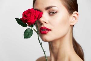 donna con lungo Tenere fiore vicino viso rosso labbra acconciatura chiaro pelle foto